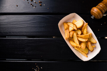 Rustic style golden crispy fried potato wedges sprinkled in box. Takeaway food in fast food restaurant