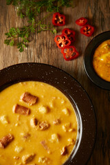 Mote pata is a traditional ecuadorian soup made from mote, pork, sausage and sambo seeds. It’s served on a white plate with a rustic, wooden and homey background. 