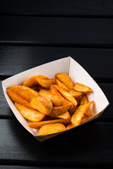 Rustic style golden crispy fried potato wedges sprinkled in box. Takeaway food in fast food restaurant