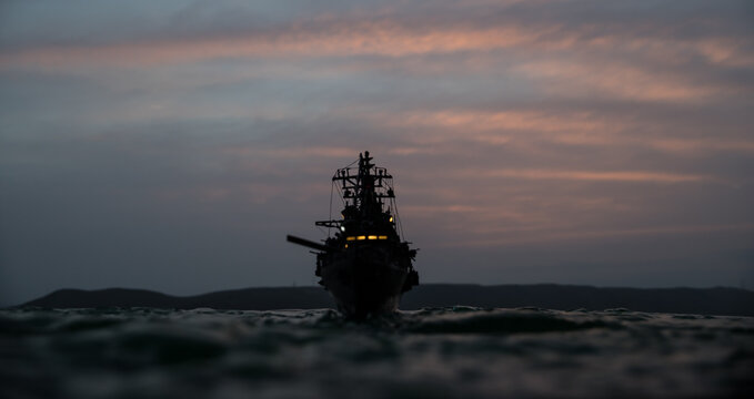 Silhouettes of a crowd standing at blurred military war ship on foggy background. Selective focus. © zef art