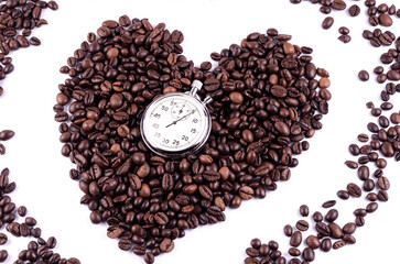 Coffee beans laid out in the shape of a heart on a white background with a stopwatch, time to drink coffee