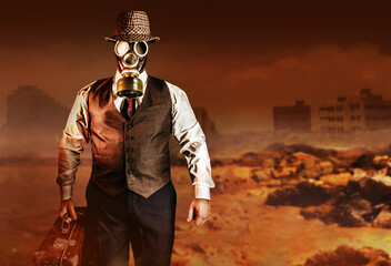 Photo of post apocalyptic male citizen in formal outfit, hat, gas mask and suitcase walking on...