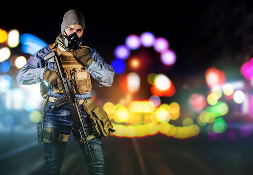 Photo of urban soldier in tactical military outfit and gas mask standing with rifle and gas mask on night neon city background.