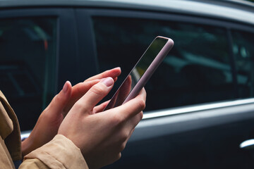 Woman holding mobile phone in hands. Carsharing. 