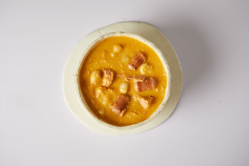 Mote pata is a traditional ecuadorian soup made from mote, pork, sausage and sambo seeds. It’s served on a white plate with a white background