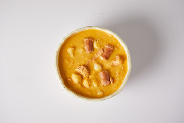 Mote pata is a traditional ecuadorian soup made from mote, pork, sausage and sambo seeds. It’s served on a white plate with a white background
