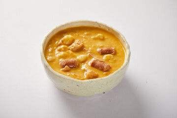 Mote pata is a traditional ecuadorian soup made from mote, pork, sausage and sambo seeds. It’s served on a white plate with a white background