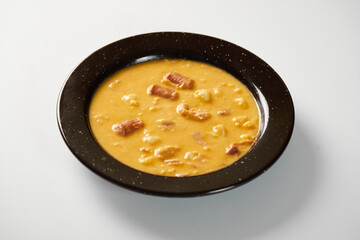 Mote pata is a traditional ecuadorian soup made from mote, pork, sausage and sambo seeds. It’s served on a white plate with a white background