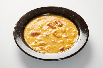 Mote pata is a traditional ecuadorian soup made from mote, pork, sausage and sambo seeds. It’s served on a white plate with a white background