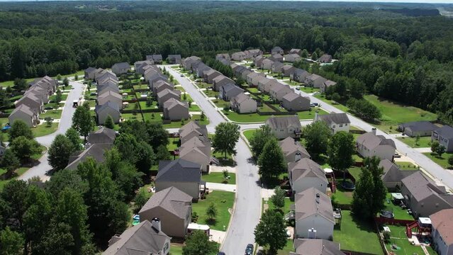 Pull away drone aerial view over an American lush green suburban neighborhood.