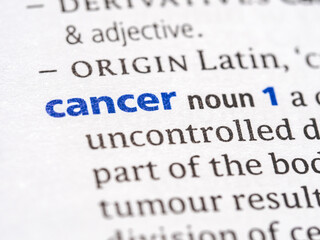 Obraz premium Cancer - English dictionary definition of the word - photo of a dictionary page with paper grain texture - selective focus on the word