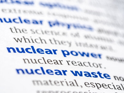 Nuclear power - English dictionary definition of the word - photo of a dictionary page with paper grain texture - selective focus on the word