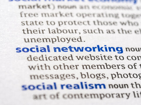 Social networking - English dictionary definition of the word - photo of a dictionary page with paper grain texture - selective focus on the word