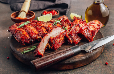 Mexican barbecued ribs seasoned with a spicy tomato sauce served on a wooden chopping board on a dark background.