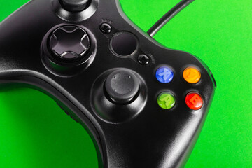 Close up photo of classic wired modern game pad controller laying on green background. © breakermaximus
