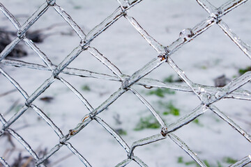 Close up photo of frozen metal fence surface covered in ice texture.