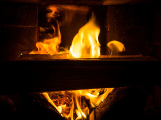 Burning firewood in a fireplace in a country house. Rustic stove with burning logs close-up.