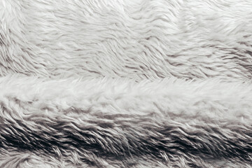 Backdrop close-up photo texture of light colored synthetic fur fold material.