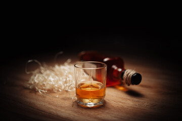 Glass of whiskey on wooden dark background with bottle