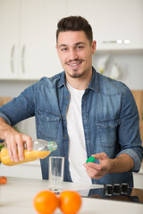 Fototapeta na wymiar happy handsome man pouring a glass of fresh orange juice