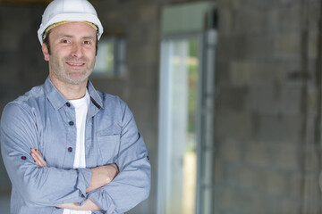 handsome builder is posing with armscrossed