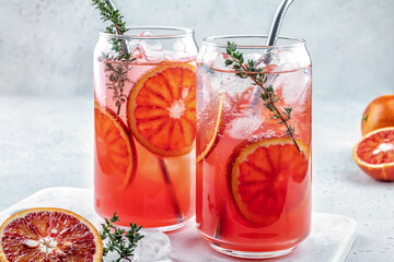 Blood Orange lemonade cocktail with ice and thyme on light gray concrete background