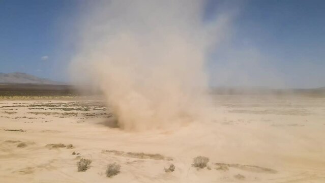 Swirling dust devil races across the desert from aerial perspective