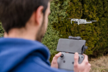 Close-up of a young man flying and watching a drone outdoors