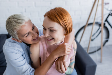 happy woman embracing lesbian girlfriend at home