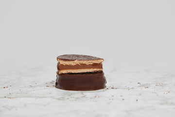 Dark chocolate alfajores with dulce de leche on a marble table