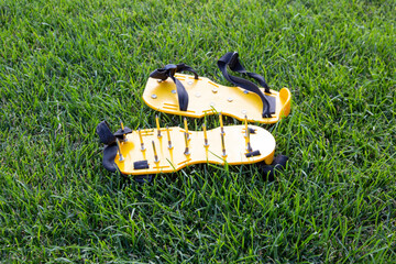 Yellow lawn aerator sandals with nails for lawn cultivation. Shoes with aeration spikes for...