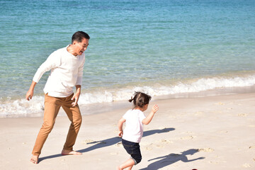 青い海、白い砂、追いかけっこしながらはしゃぐおじいちゃんと孫娘