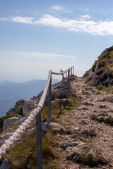 Fototapeta na wymiar Pedestrian road in the mountains of Croatia with rope fence, vertical orientation