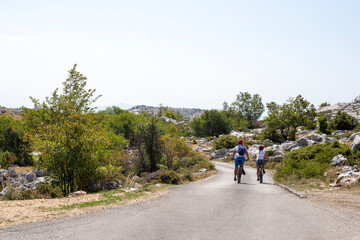 Man and woman ride bicycles on mountain road in summer