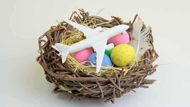 White plane and easter eggs in nest. Spring easter season, travel concept background.