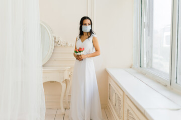 African American bride in dress, mask and in the morning preparing for the wedding in hotel room