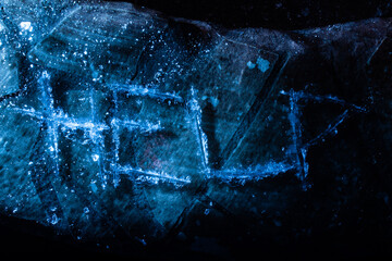 Photo of help word scratched on cracked ice surface on dark background.