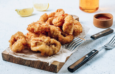 Breaded rings of squid with lemon on a white background. Snack to beer.
