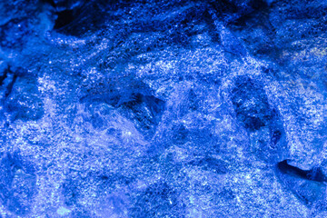 Photo of blue toned frozen wooden coal covered in ice surface texture.