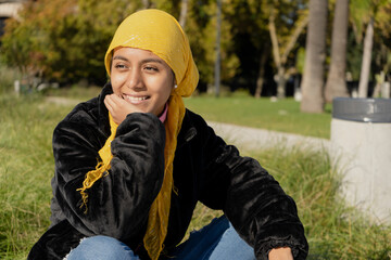 Young Latina survivor of cancer, with a scarf covering her head