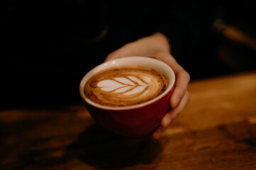 Hand Holding Latte Art in Red Mug