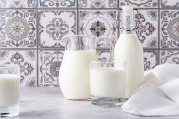 Milk in a glass, decanter and bottle on a light background
