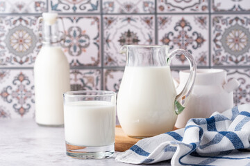 Milk in a glass, decanter and bottle on a light background