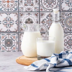 Milk in a glass, decanter and bottle on a light background