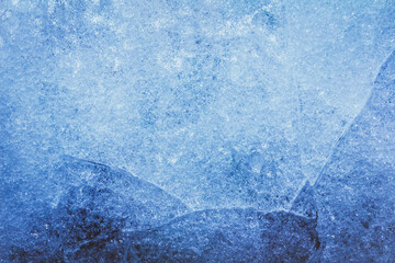 Photo of blue toned frozen cracked ice surface texture.