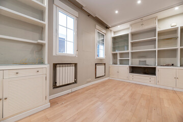 Living room with plaster and wood furniture embedded in the wall, wooden flooring and white aluminum radiators
