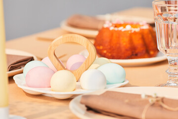 Close up of pastel colored Easter eggs on elegant dinner table decorated for Spring, copy space