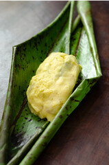 Native woman cooking typical Colombian and Mexican traditional dish made with corn dough and stuffed with chicken, pork, pork ribs, vegetables; wrapped in banana leaves, steamed.