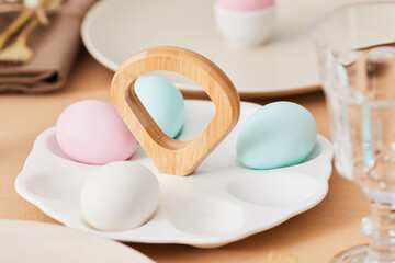 Close up of pastel colored Easter eggs placed on cute platter at dinner table decorated for Spring, copy space