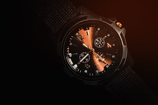 Shaded photo of military tactical watch with copper elements on black background.